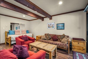 Um quarto acolhedor com uma cama, dois sofás, uma mesa de centro de madeira e um aparador.