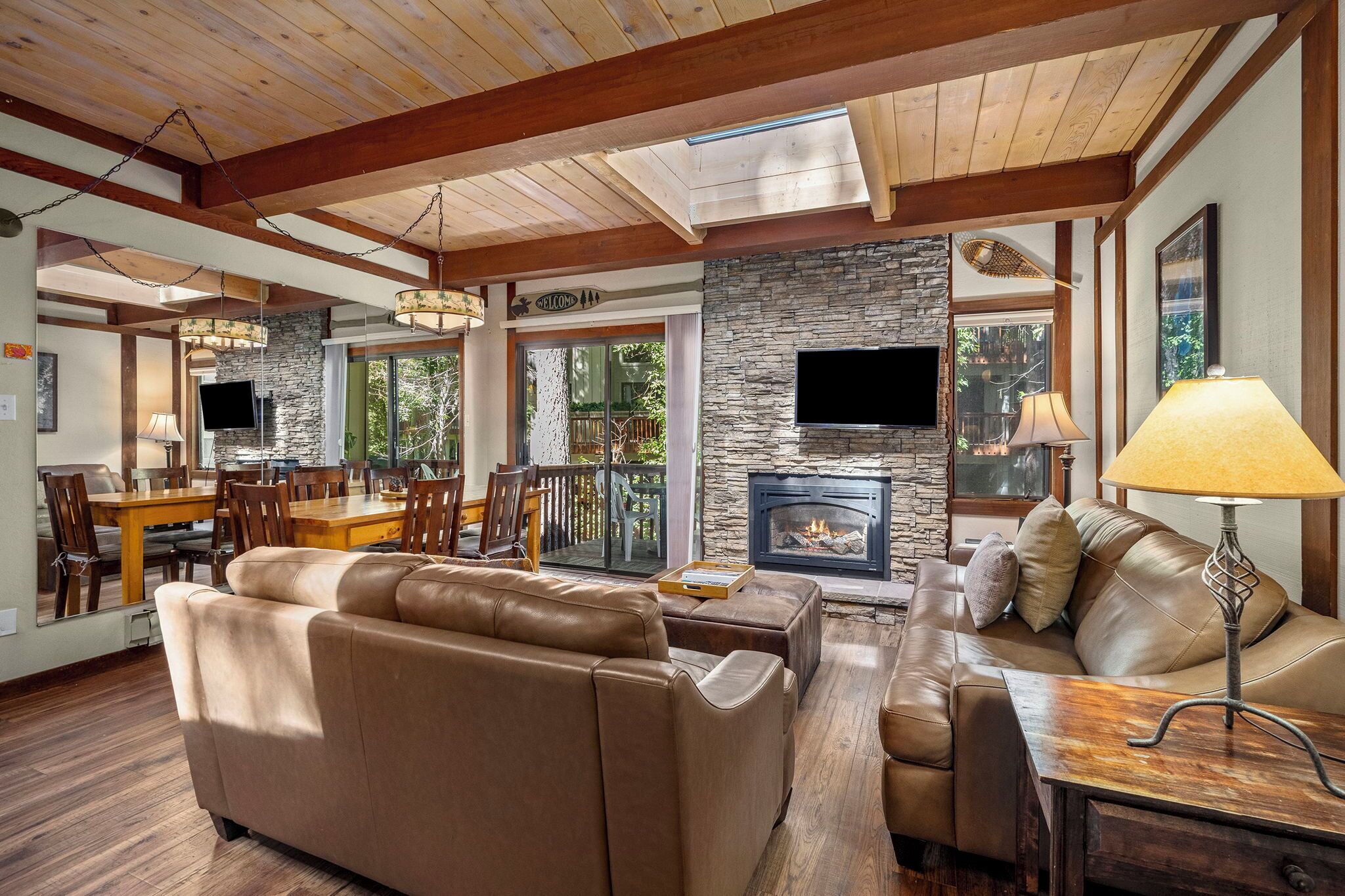 A spacious living room with a stone fireplace, leather sofas, and a dining area with a wooden table and chairs.