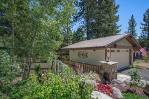 A lodge with a garage, surrounded by dense forest and a variety of plants. - 1366 Zurich | 3BR/3.5BA Incline Village (Incline Village)