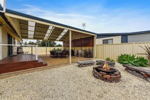 Une terrasse extérieure couverte avec un espace barbecue, des sièges et un foyer.