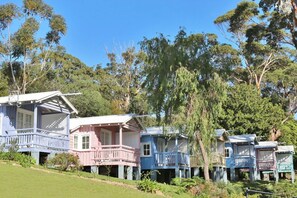 Una hilera de casas de madera tradicionales con porches, rodeadas de exuberante vegetación.