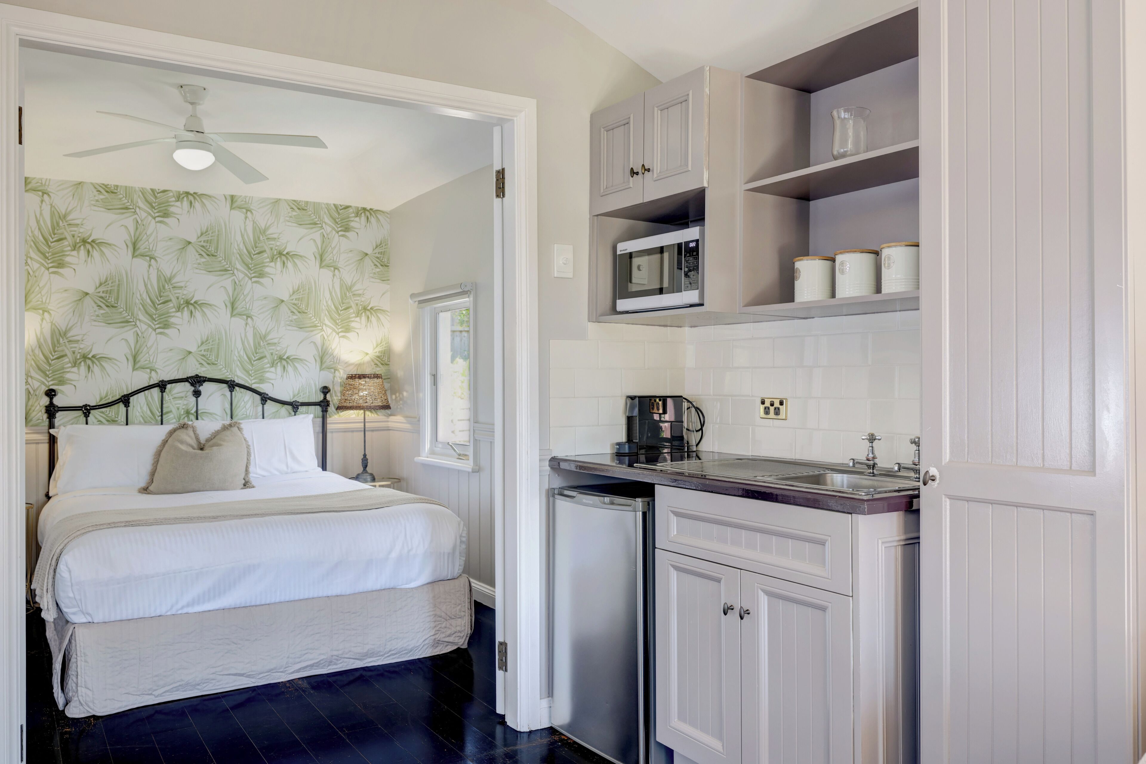 A bedroom with a bed, a ceiling fan, and a nightstand with a lamp.