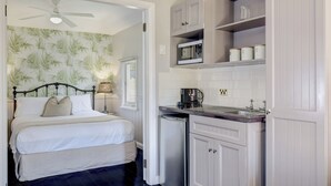 A bedroom with a bed, a ceiling fan, and a nightstand with a lamp.