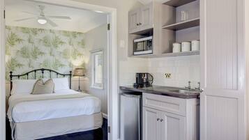 A bedroom with a bed, a ceiling fan, and a nightstand with a lamp.