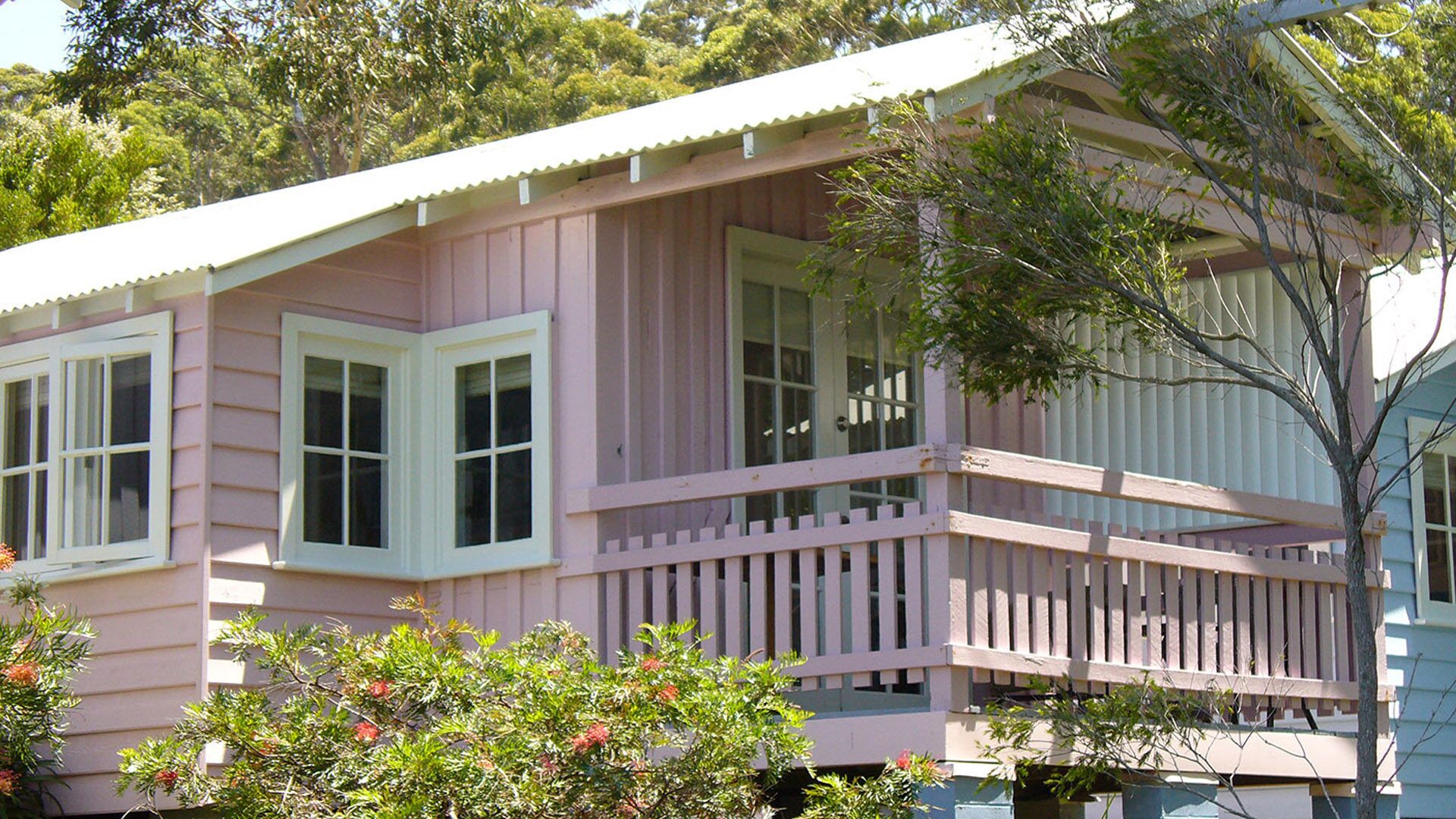 A pink house with a balcony and a porch.