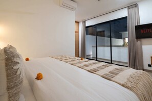 A hotel room with a large bed, a view of the outside, and a sign indicating a Netflix service. - Villa Puligny (Tibubeneng)