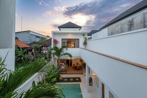 A modern house with a pool, surrounded by lush greenery and a clear sky. - Villa Puligny (Tibubeneng)