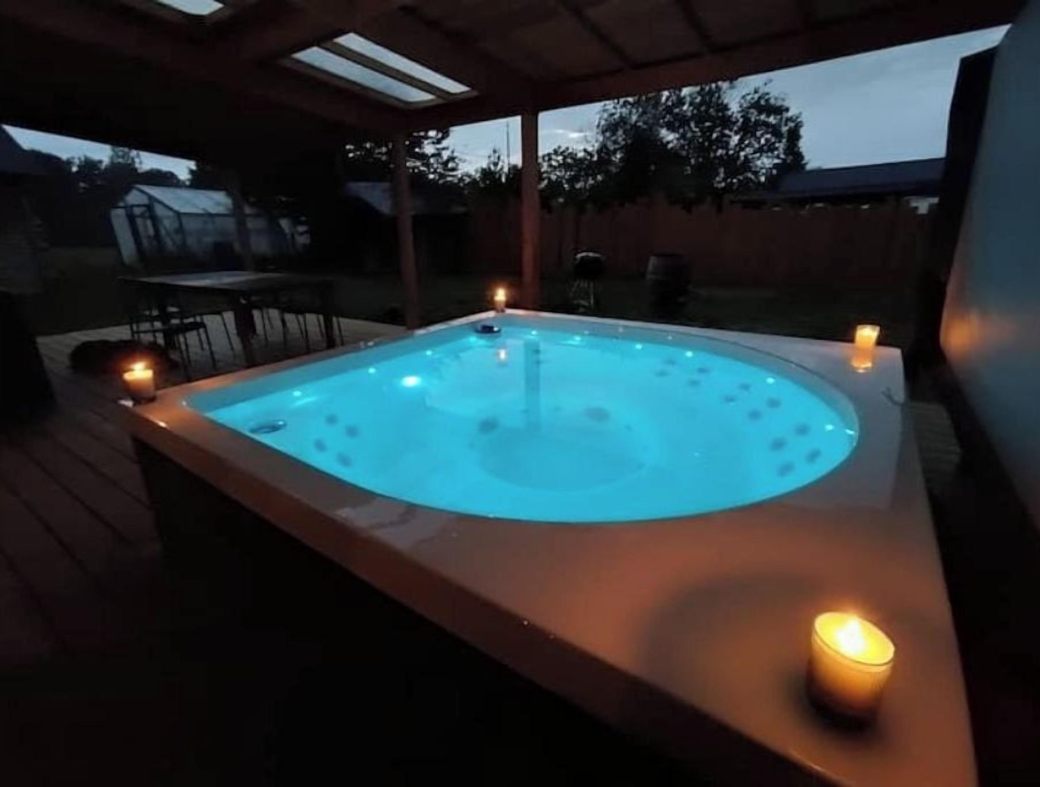 A hot tub with a wooden deck and two candles.