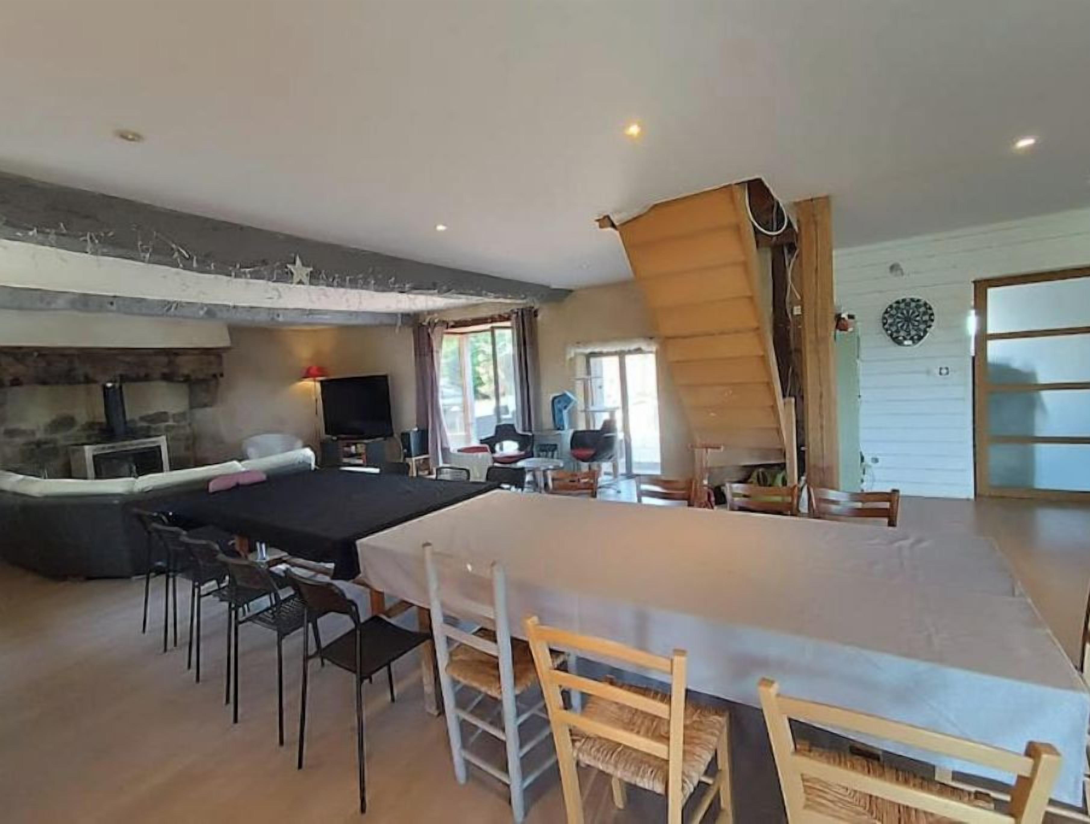 Amplia sala de estar con una gran mesa de comedor, una chimenea y vistas al exterior.