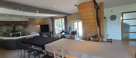 A spacious living area with a large dining table, a fireplace, and a view of the outdoors.
