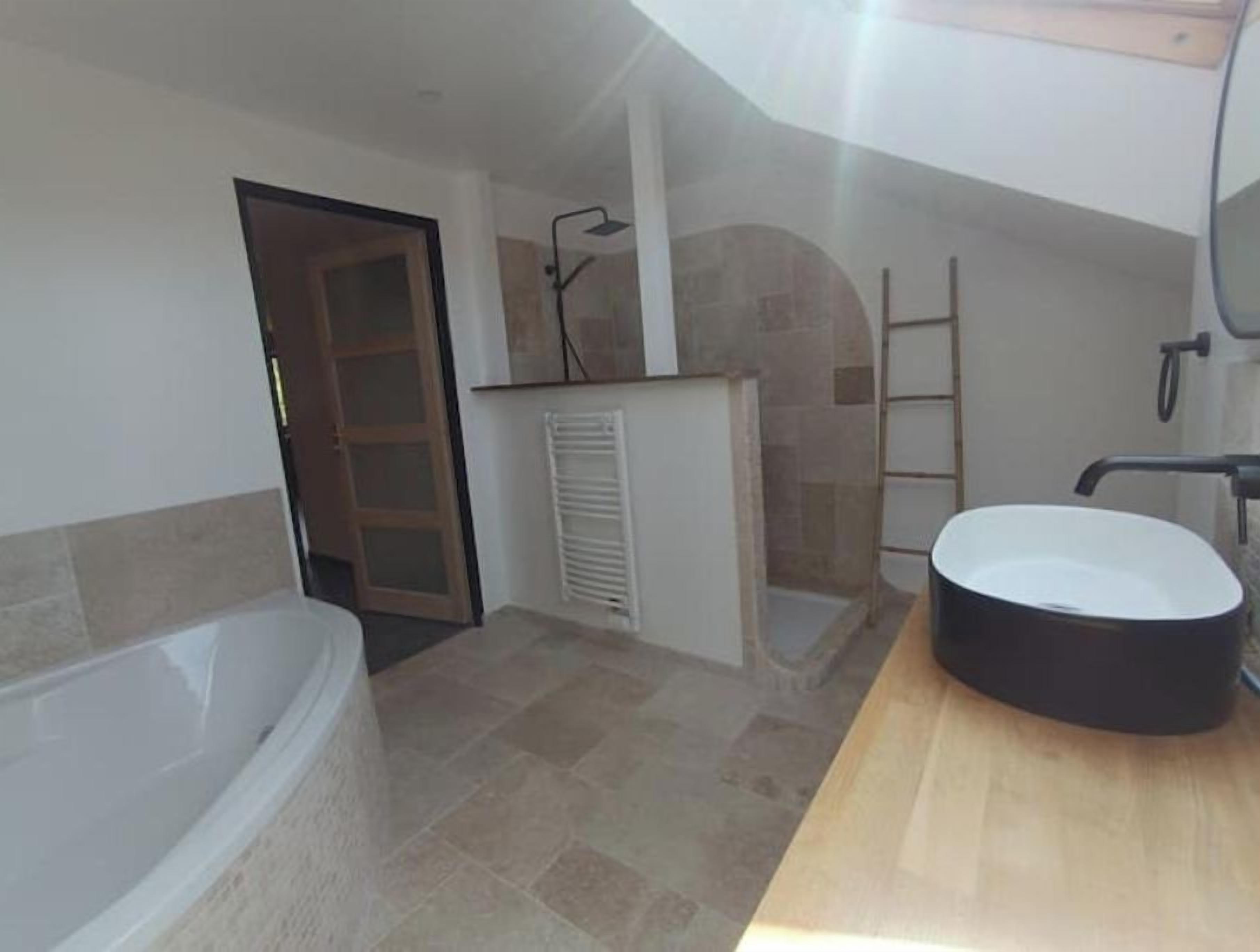 A bathroom with a bathtub, a sink, and a shower area.