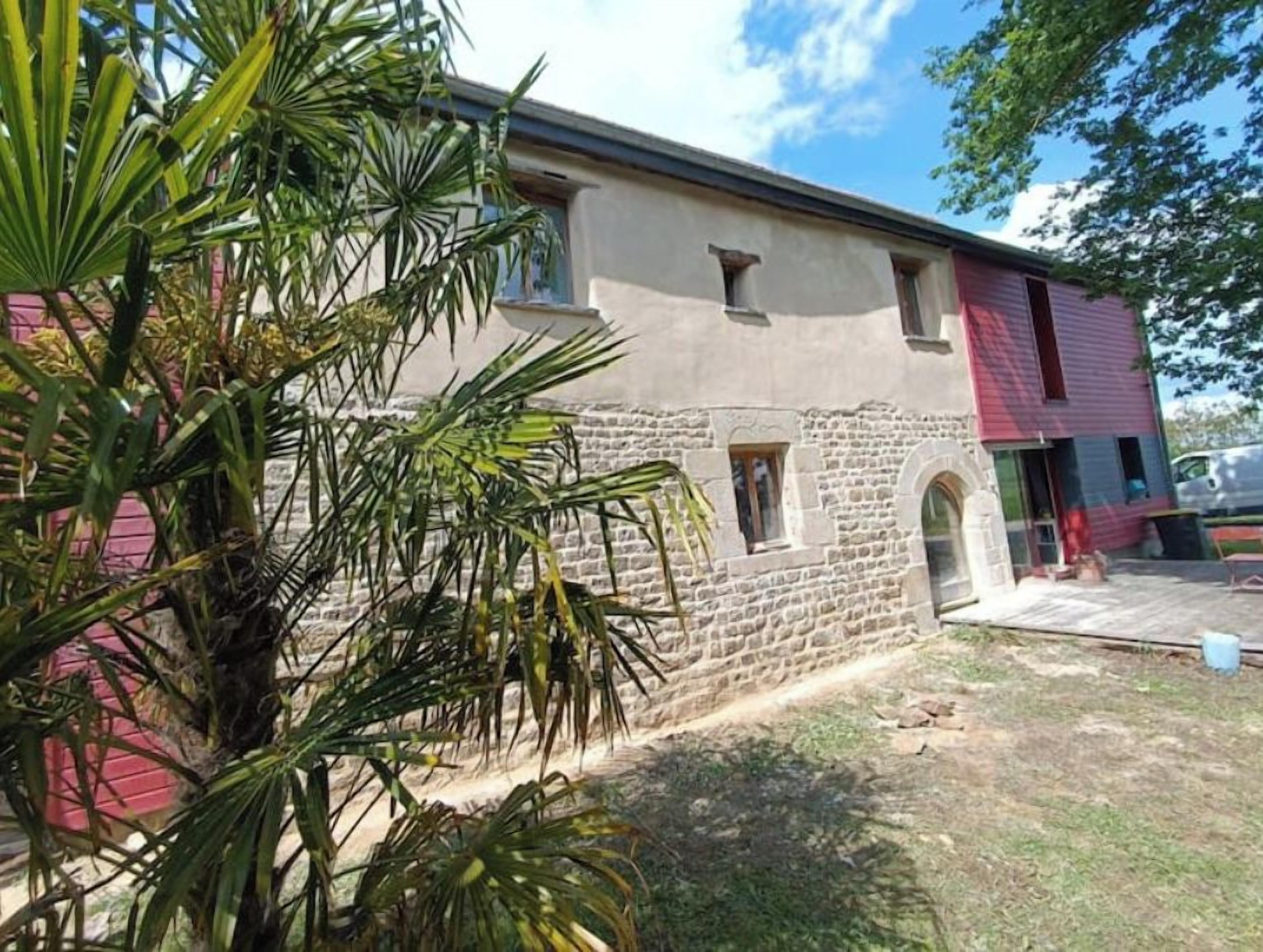 A building with a stone facade, a red roof, and a small window.
