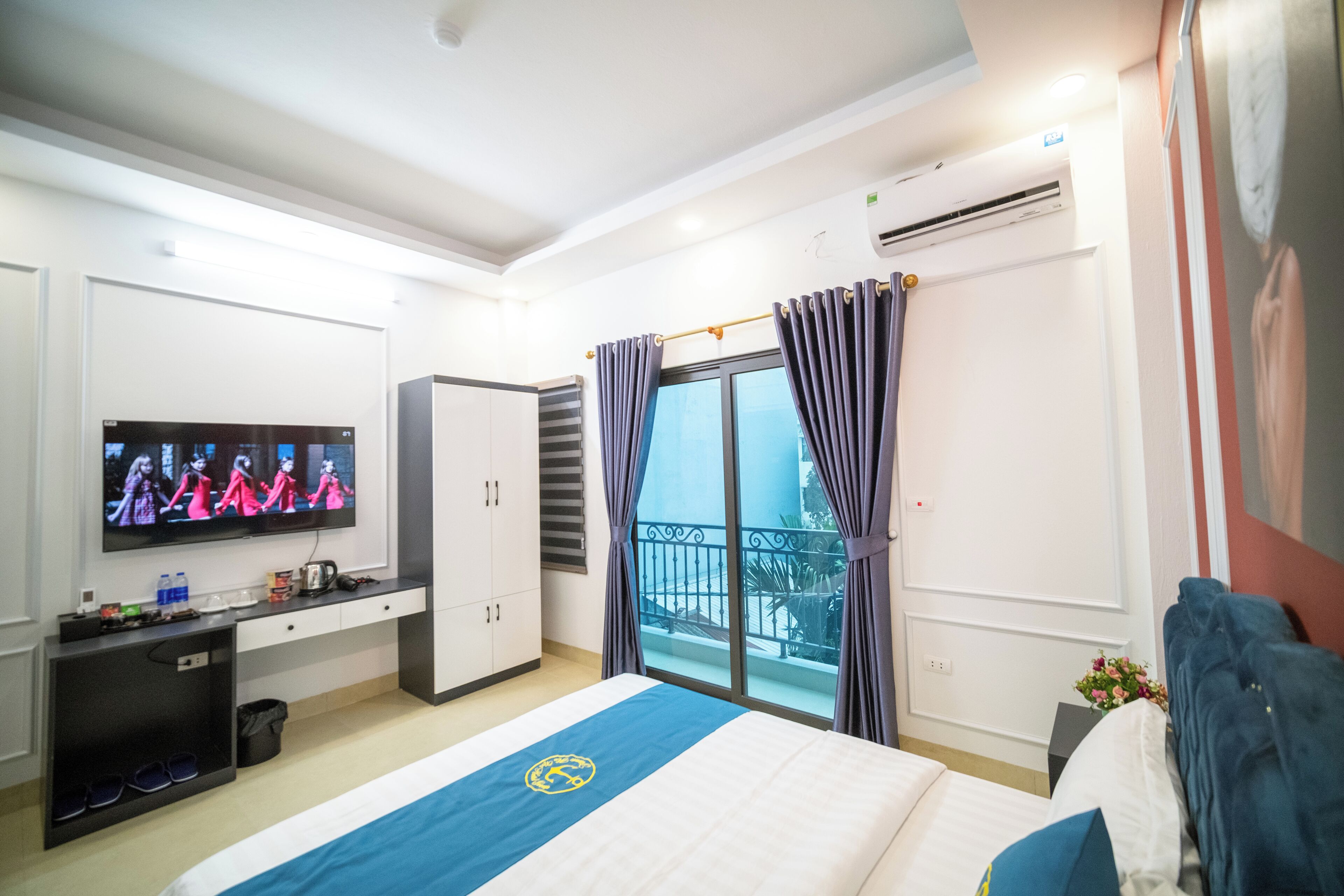 Een hotelkamer met een bed, een televisie, een bureau en een balkon.