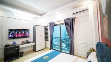 Een hotelkamer met een bed, een televisie, een bureau en een balkon.