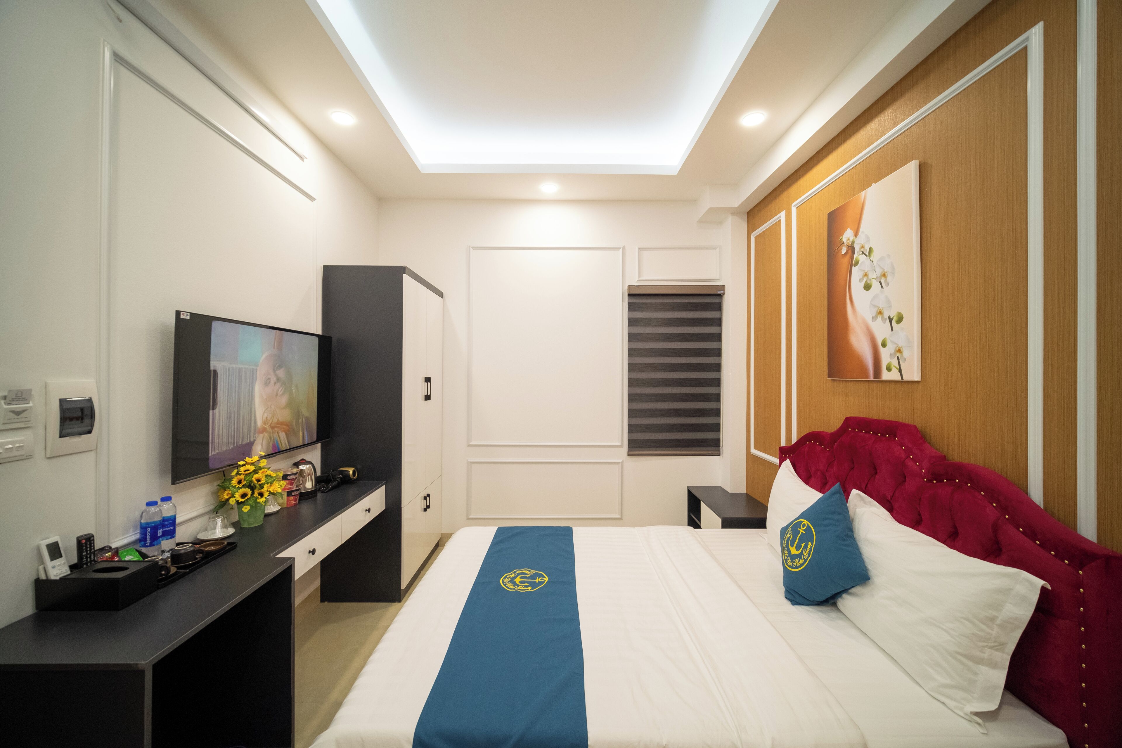 Une chambre d’hôtel avec un lit, une télévision, un bureau et une fenêtre avec des stores.