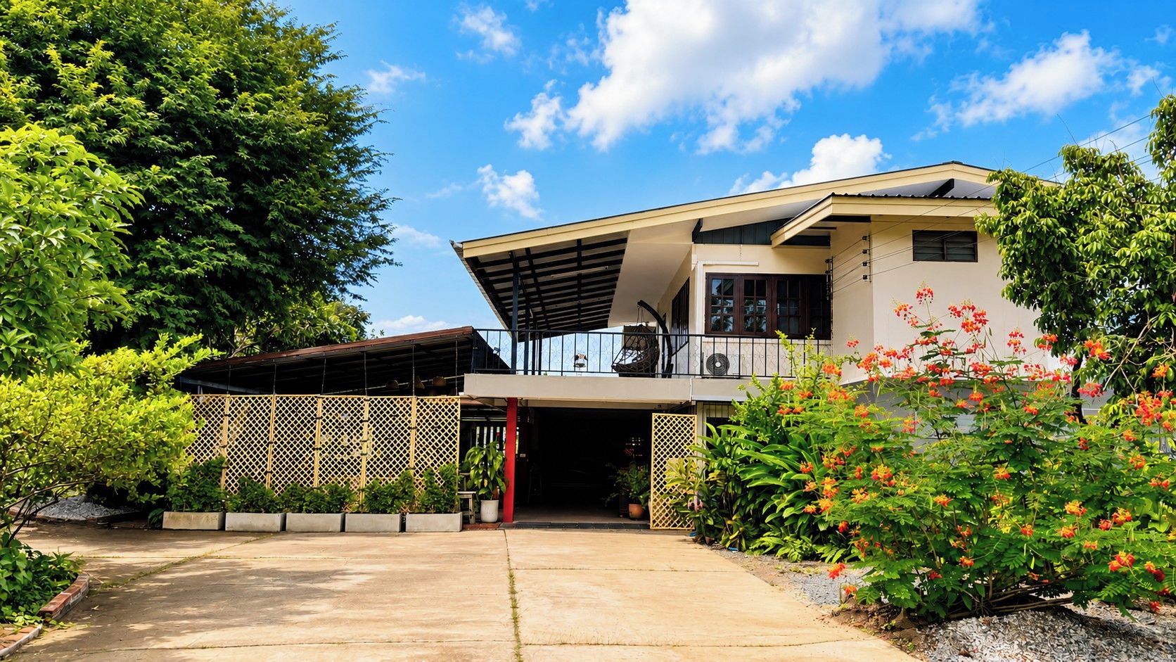 Uma casa moderna de dois andares com entrada coberta, varanda e jardim com plantas floridas.