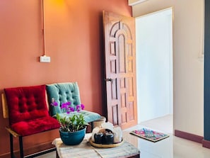 A room with a red chair, a teal chair, a blue bowl with a plant, a tray with a teapot, and a wooden door. - Retro at Mae Rim (Mae Rim)
