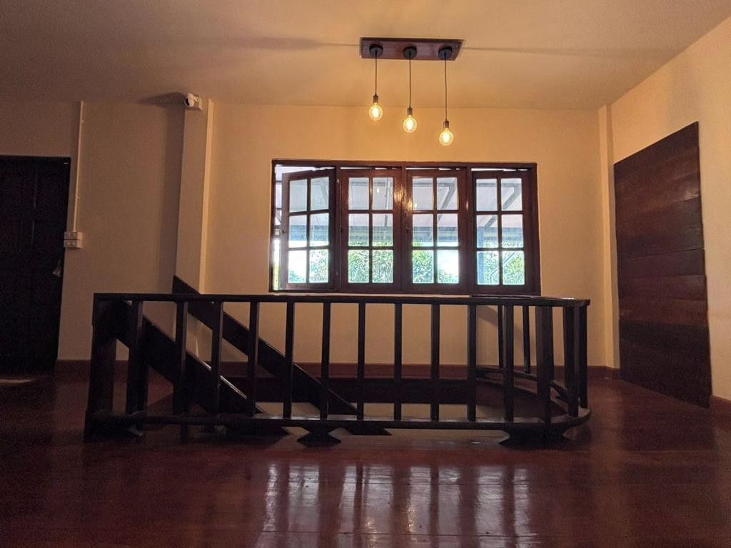 A room with a wooden floor, a black railing, and a large window with multiple panes.