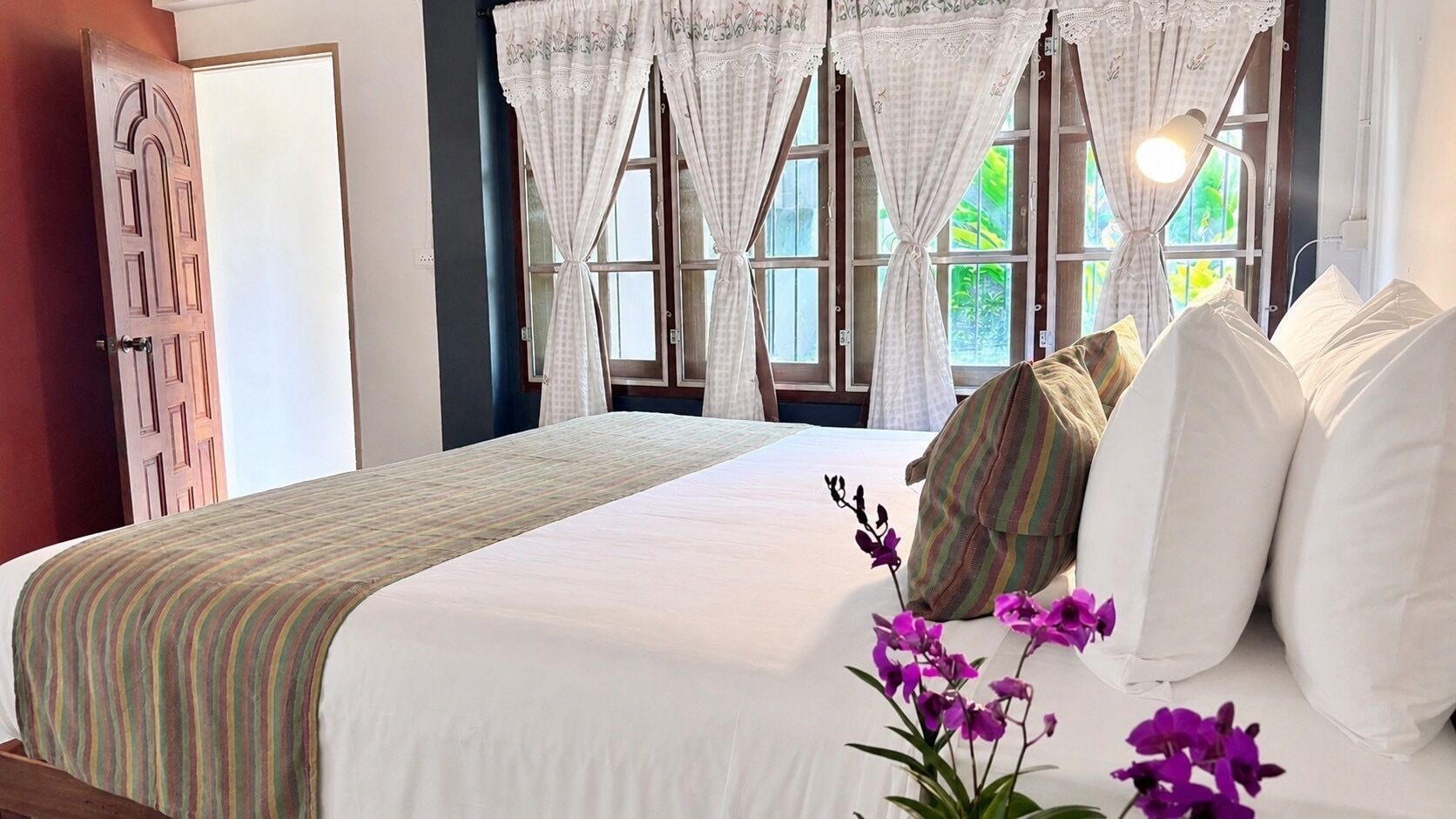 Habitación de hotel con una cama grande, cortinas blancas y vistas al exterior.