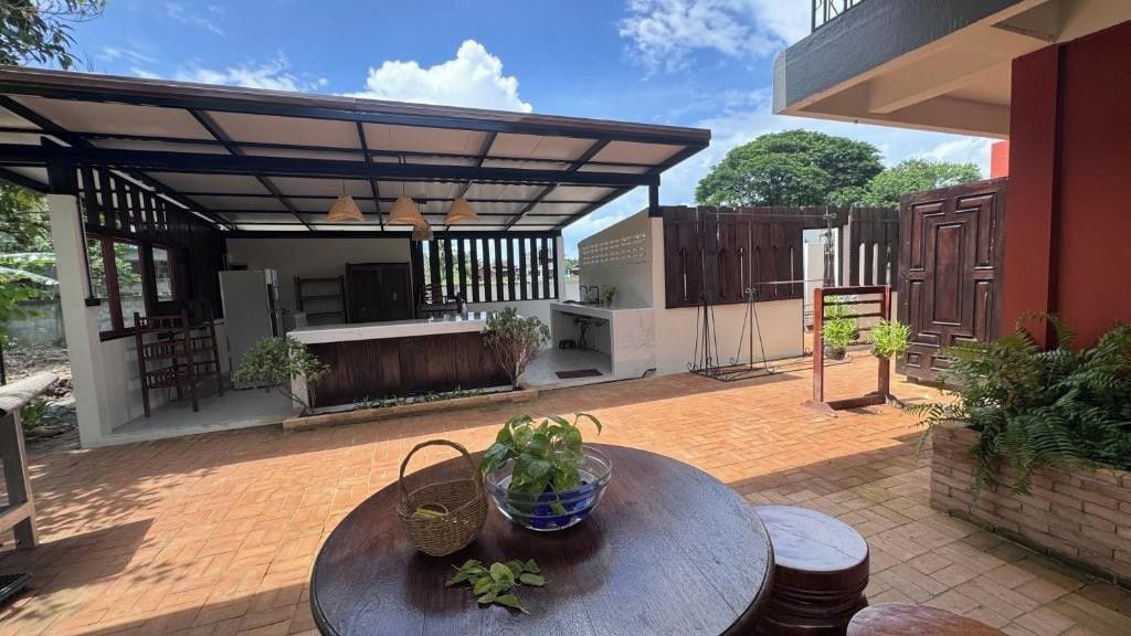 An outdoor patio area with a covered seating area, a grill, and a table with a bowl of plants.