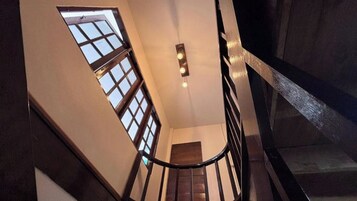 A staircase with a handrail, a light fixture, and a window.