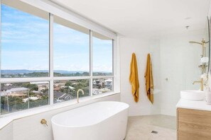 Un bagno moderno con una vasca freestanding, un'ampia finestra e vista su una zona residenziale.
