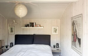 A bedroom with a bed, a white ceiling, a shelf with books, a framed picture, and a poster on the wall. - 3 bedroom stunning home in Eskebjerg (Eskebjerg)