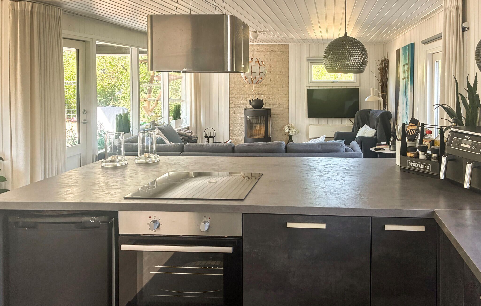 Een moderne keuken met een inbouwoven, een eethoek met een groot schiereiland, en een gezellige zithoek met een open haard.