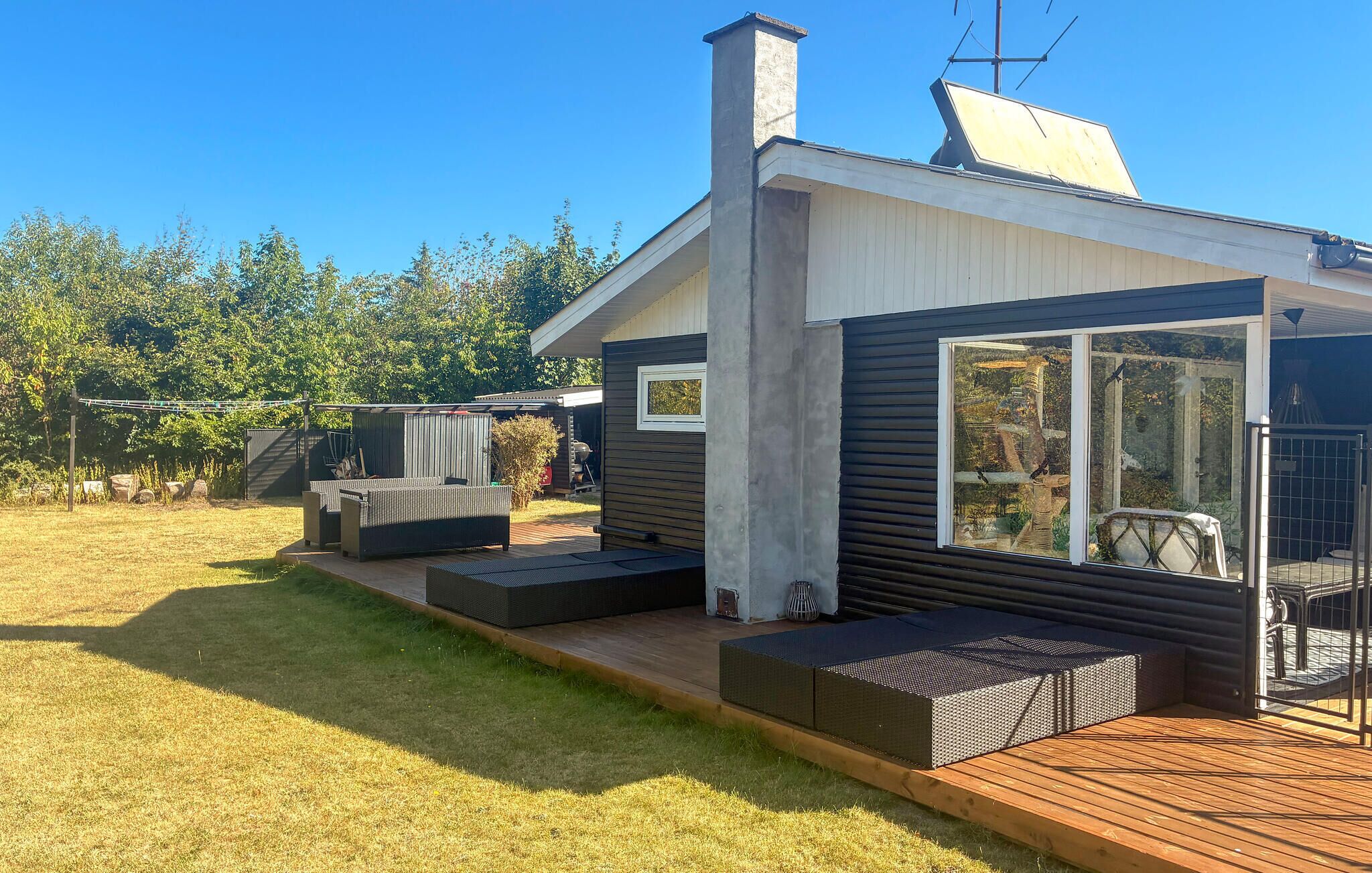 Une maison moderne dotée d’une terrasse, d’un espace salon extérieur et d’une grande fenêtre.