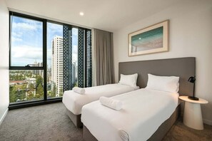A hotel room with two beds, a large window with a city view, a framed picture on the wall, and a bedside table with a lamp. - The Sea-gnature Stay | Coast & City (Gold Coast)