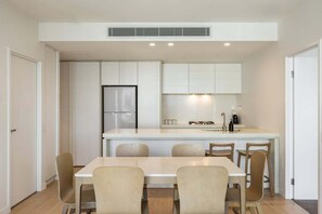 A modern kitchen with a central island, built-in cabinets, and a stainless steel refrigerator. - The Sea-gnature Stay | Coast & City (Gold Coast)