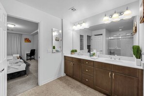 Una habitación de hotel con un baño amplio, una cama, un escritorio y una silla.