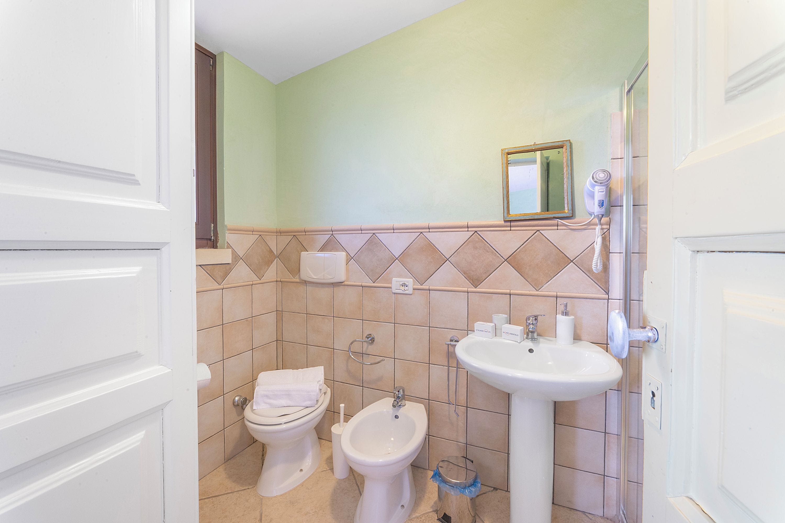 Ein Badezimmer mit Toilette, Bidet, Waschbecken und einem Spiegel an der Wand.