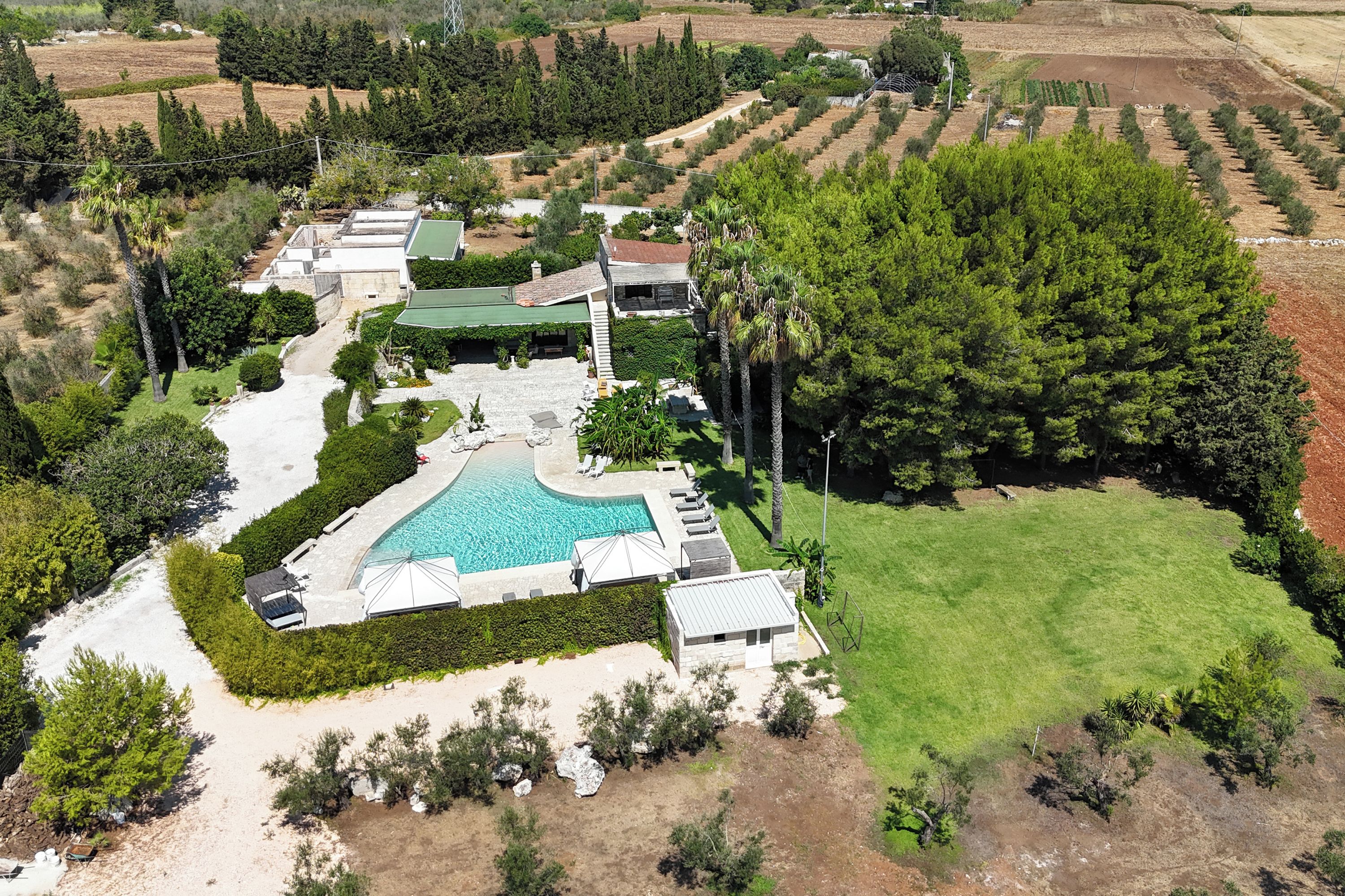 A large property with a swimming pool, multiple buildings, and landscaped gardens.
