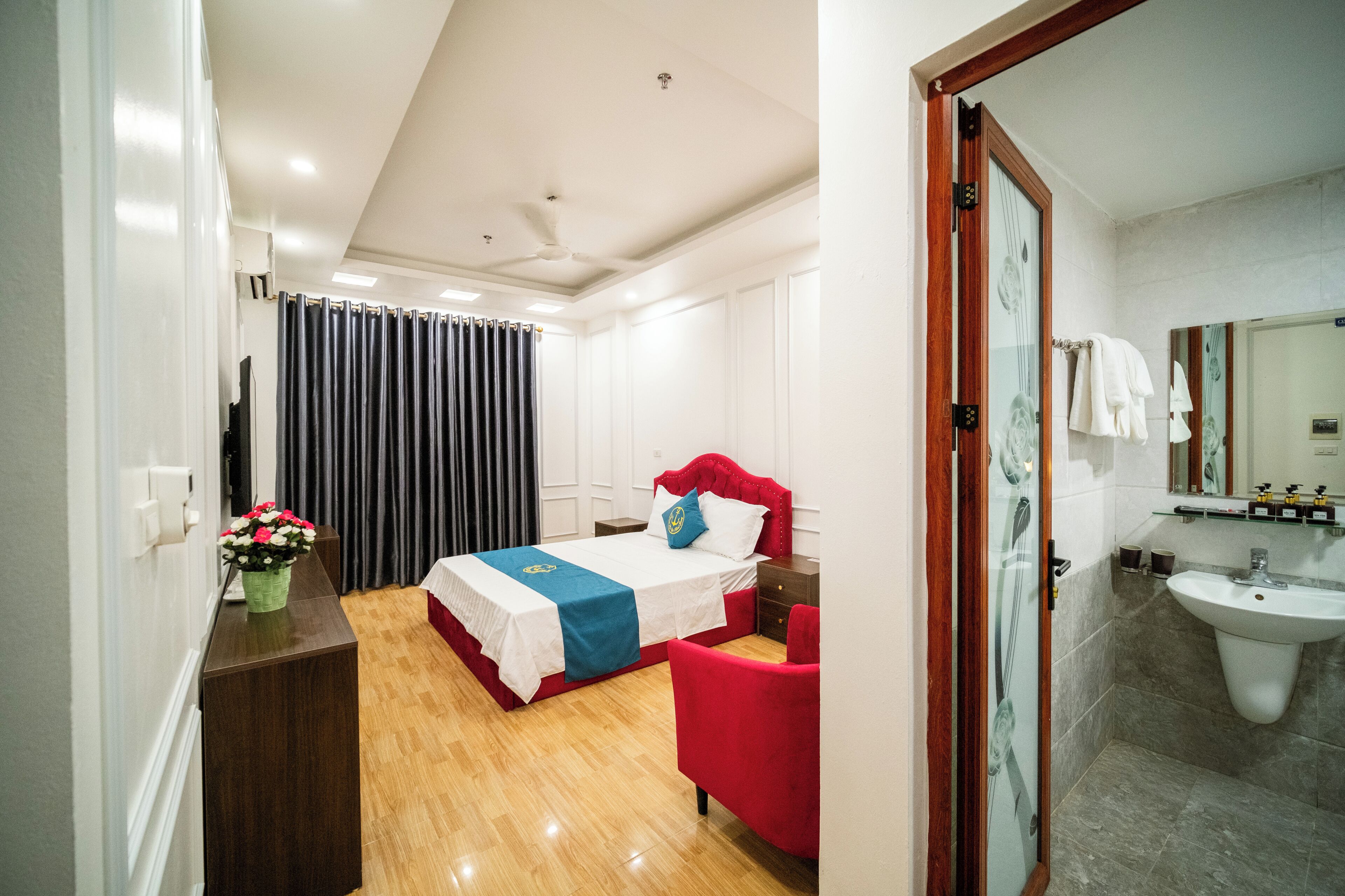 Une chambre d’hôtel avec un lit, une petite table, une chaise, un miroir et une salle de bain avec un lavabo.