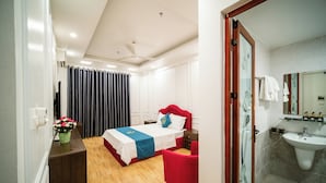 Een hotelkamer met een bed, een tafeltje, een stoel, een spiegel en een badkamer met een wastafel.