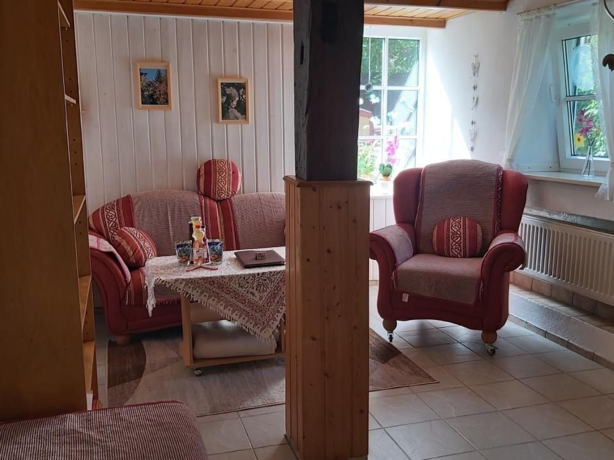 Ein gemütliches Wohnzimmer mit einer Couch, einem Sessel und einem Tisch mit weißen Tischdecken.