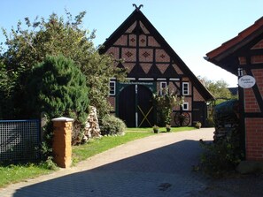 A traditional half-timbered building with a large wooden door and a sign indicating it is a guesthouse. - De lüt Ferienhof Jameln Lüneburger-Heide/Wendland by Interhome (Jameln)
