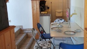 Ruokailutila, jossa on kahdelle katettu pöytä, tuolit ja taustalla keittiö.