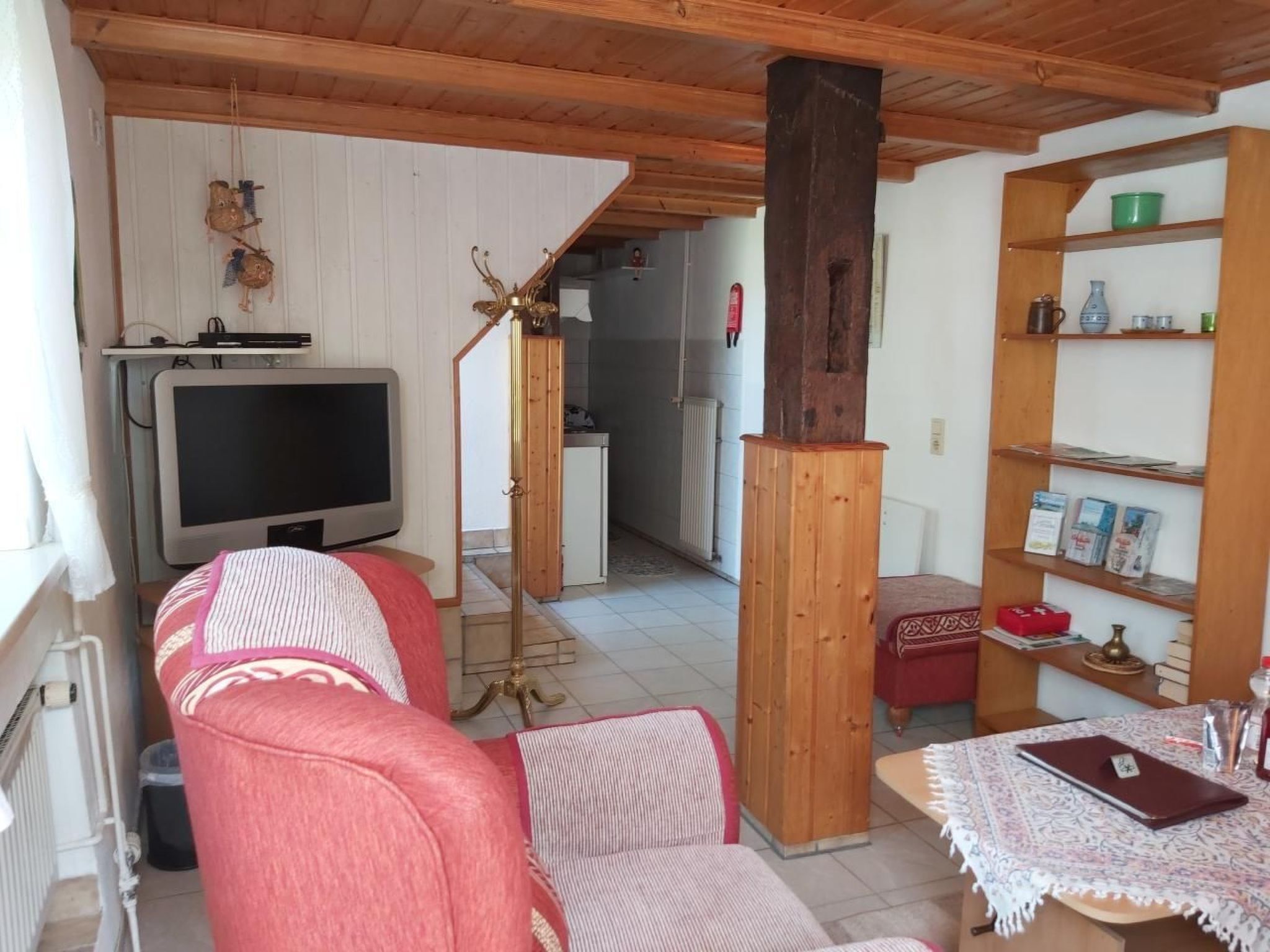 Una sala de estar con una televisión, un sofá, una mesa de centro y una estantería.