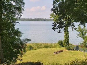 A lakeside view with a grassy area, a bench, and trees. - De lüt Ferienhof Jameln Lüneburger-Heide/Wendland by Interhome (Jameln)