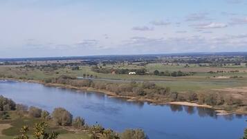 A river with a view of the countryside, including fields and a few buildings.