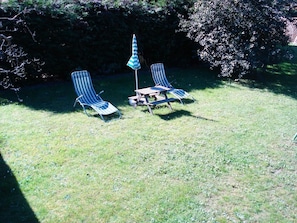 A grassy outdoor area with two striped lounge chairs and a small table, surrounded by trees. - De lüt Ferienhof Jameln Lüneburger-Heide/Wendland by Interhome (Jameln)