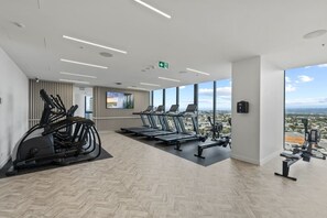 Une salle de sport moderne équipée de tapis de course, de vélos elliptiques et d’un écran de télévision.