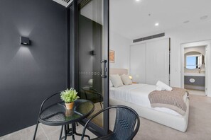 Une chambre à coucher moderne avec un lit, une table de chevet et un petit coin salon comprenant une table et des chaises.