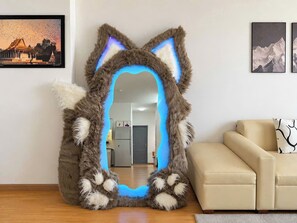 Una habitación con un espejo grande con forma de cabeza de gato, un sofá color beige y un cuadro en la pared.