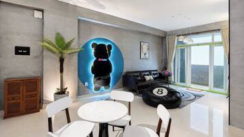 A modern living room with a glass door leading to a balcony, a black sofa, a coffee table with a number, and a potted plant.