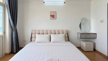 Un dormitorio con una cama grande, una mesita de noche, un espejo y una ventana con cortinas.
