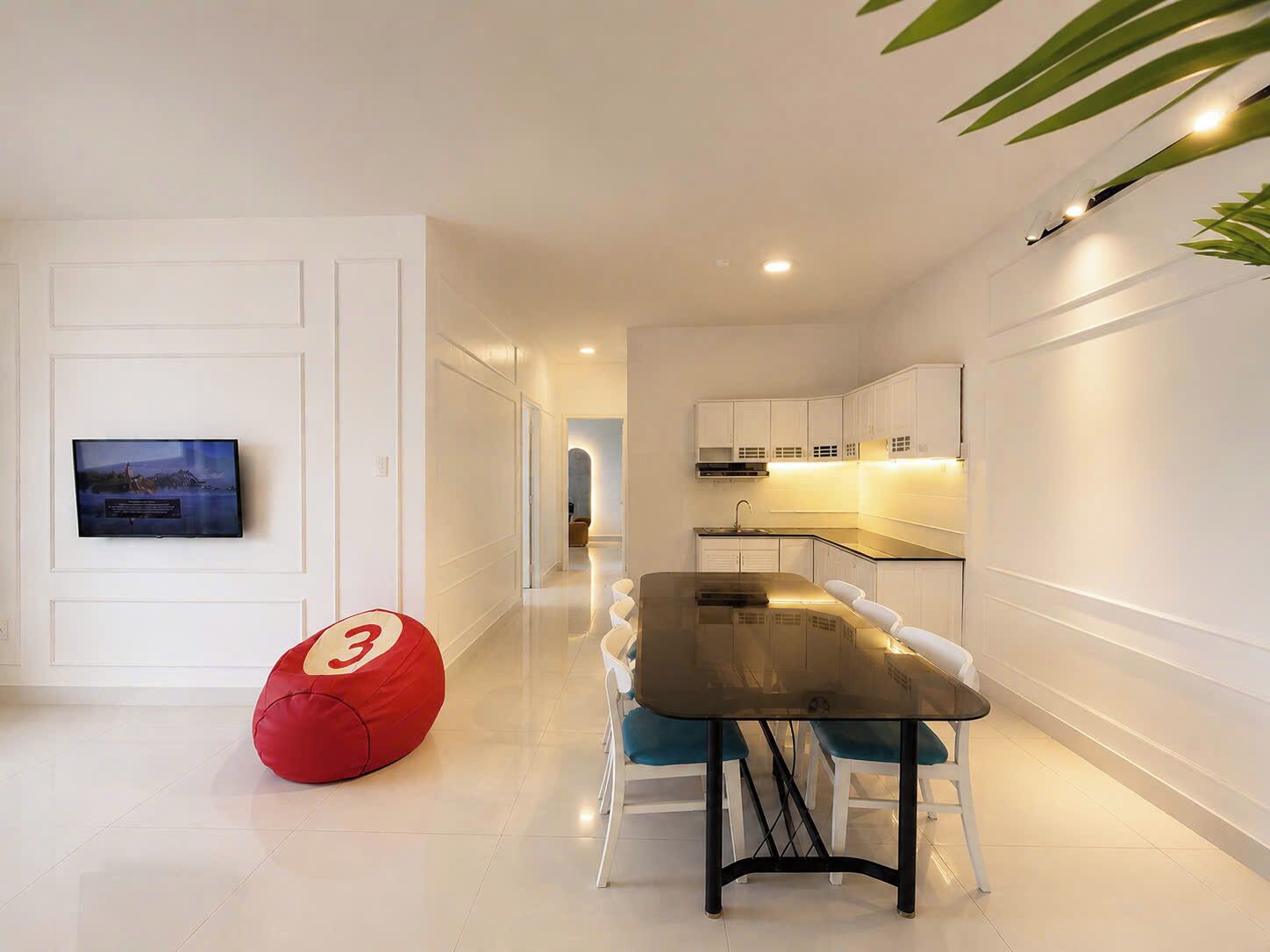 Una cocina moderna con armarios blancos, una mesa de comedor con sillas y un sillón de peluche rojo.