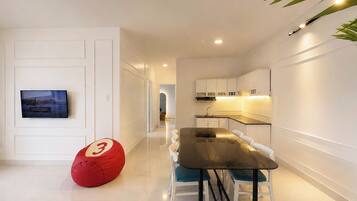Una cocina moderna con armarios blancos, una mesa de comedor con sillas y un sillón de peluche rojo.